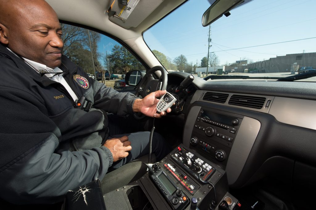 First responder in vehicle holding a radio communications device