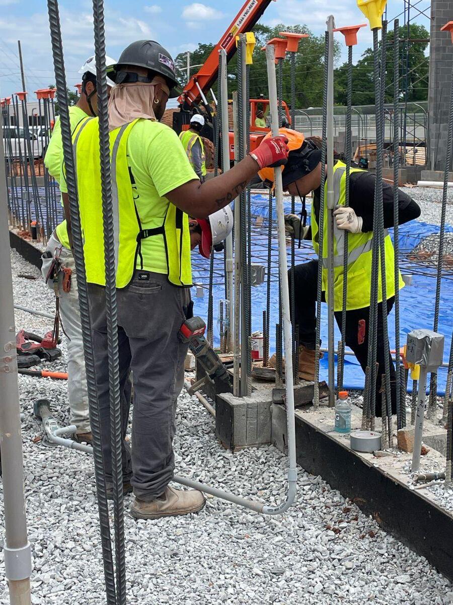 Fire station 9 Construction three men driving metal stakes into ground