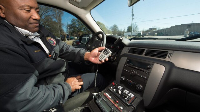 First responder in vehicle holding a radio communications device