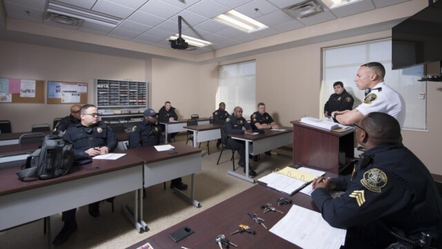 man at podium speaking to his officers seated at tables in front of him