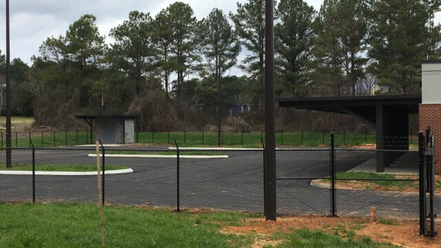 fenced in parking lot with view of covering to entrance of back of the building