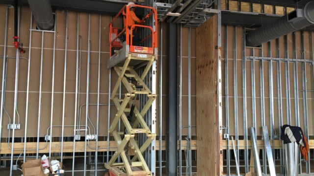 man inside building on lift truck risen to top