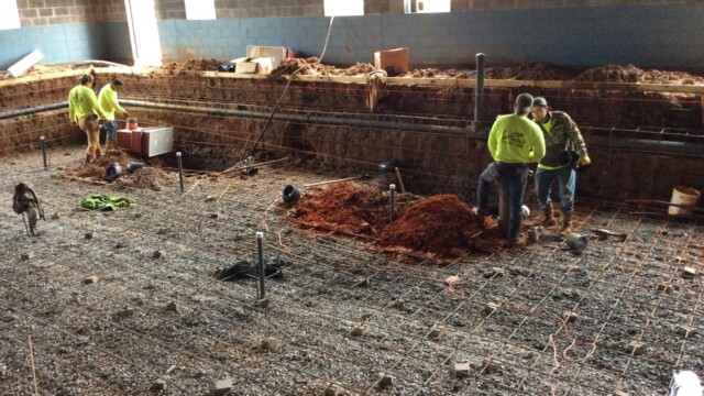 inside new building with hole dug out of floor for new pool and 4 workers