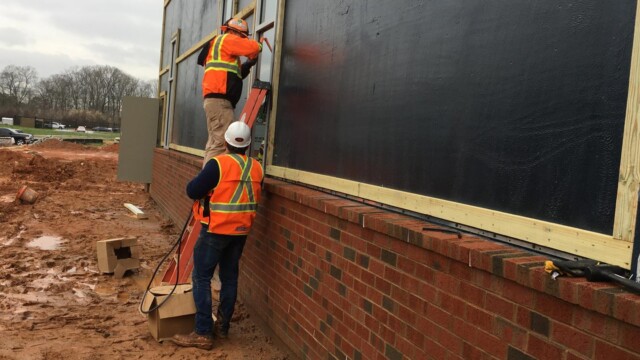 2 men working near window on new building