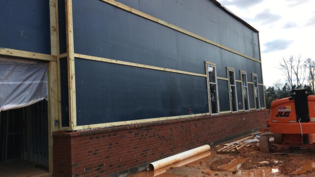 side of new building without exterior wall and construction equipment in front