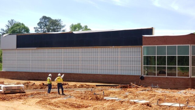 side view of building under construction with 2 workers in front