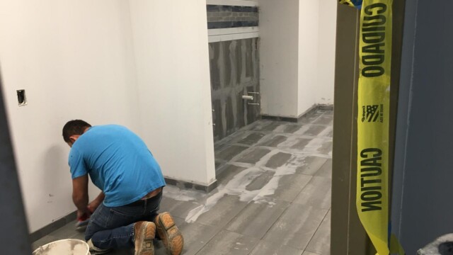 A worker applying grout to floor tiles