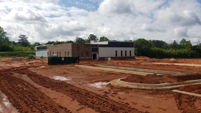 building under construction view from side with concrete parking lot edges and mud