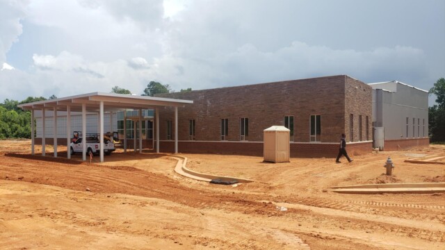 new building almost done with port-a-potty in front and man walking