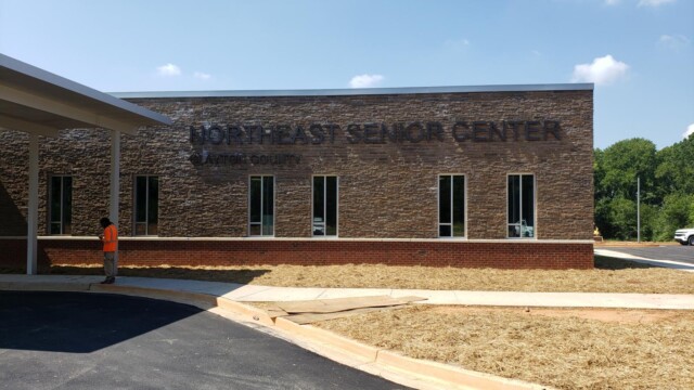 view of "Northeast Senior Center" text on building with man in orange nearby