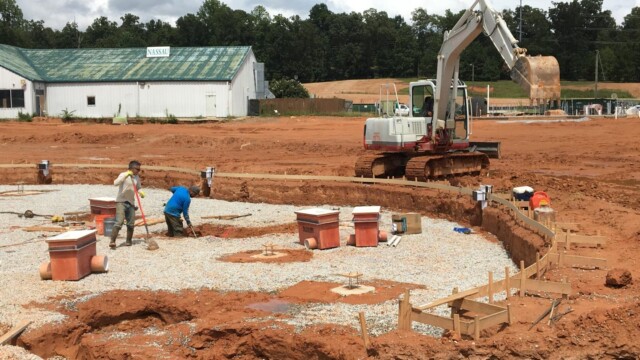 excavator and construction workers dig a pool for plumbing fixtures