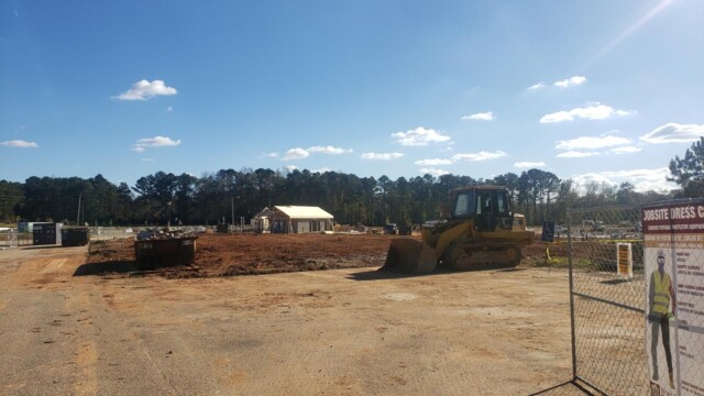 Bulldozer in the dirt next to dumpster