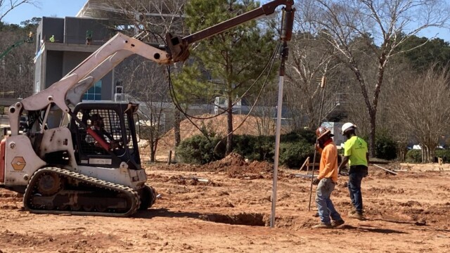 Skid Steer Loader placing metal pipe