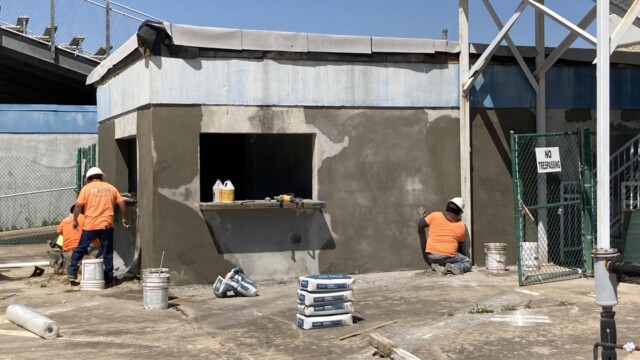 Workers surfacing cement for a concessions stand near VIP Complex