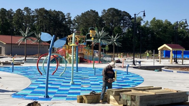 Worker sanding lumber beams near the Splash pad area