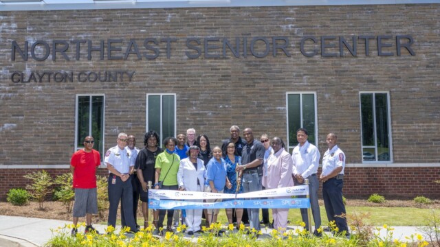 Ribbon cutting in front of building with various people including Commissioners Gail hambrick, Sonna Singleton, Alieka Anderson-Henry, DeMont Davis, and Chairman Jeff Turner