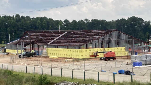 Metal framing for building with yellow wall borders and truck in the entrance