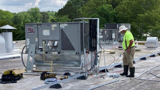 HVAC professional on rooftop wiring equipment