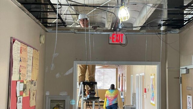 Construction worker on a ladder working on ceiling area