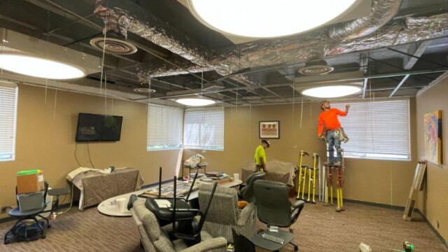Worker on stilts working on room lighting