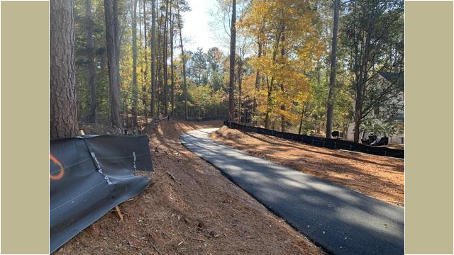 freshly poured asphalt trail with trees along the sides and pine straw on edges