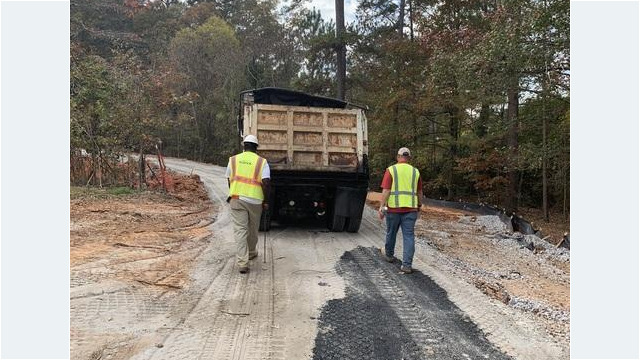 two workers follow behind truck on path