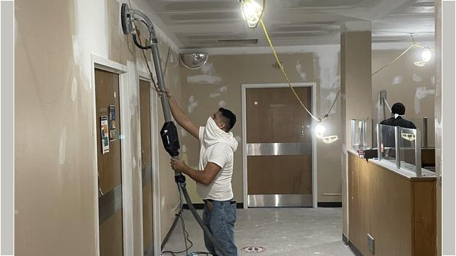 Worker sanding drywall