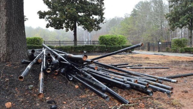 A pile of metal fenceposts under a tree