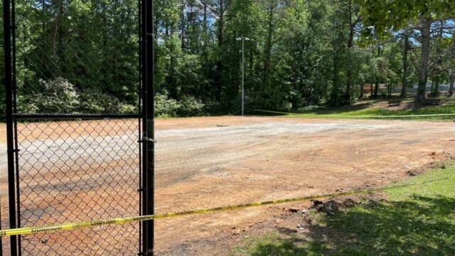 Caution tape around dirt of tennis court site