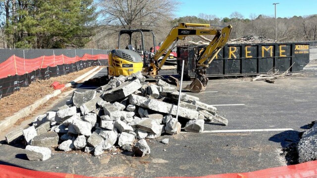 broken pieces of concrete with forklift and dumpster in background