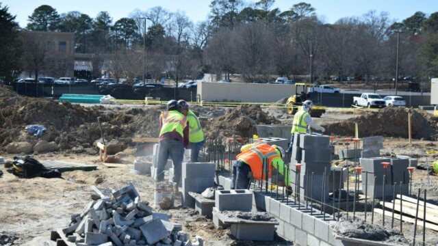 Four construction workers handling cinder blocks