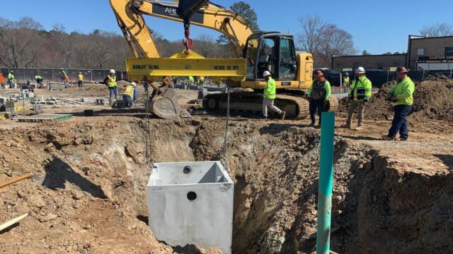 construction workers with crane showing cement fixture in ground