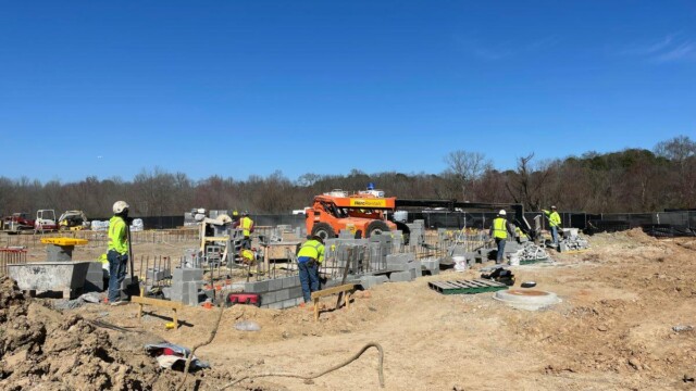 Construction workers putting concrete blocks on rebar
