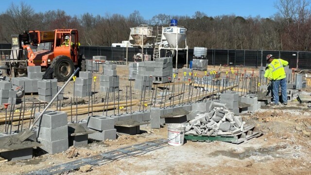 row of concrete blocks on poles with forklift in background